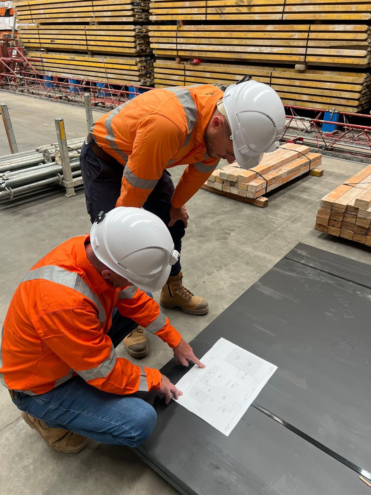 Two Conlon Contracting workers in hi-vis and hard hats reviewing a plan